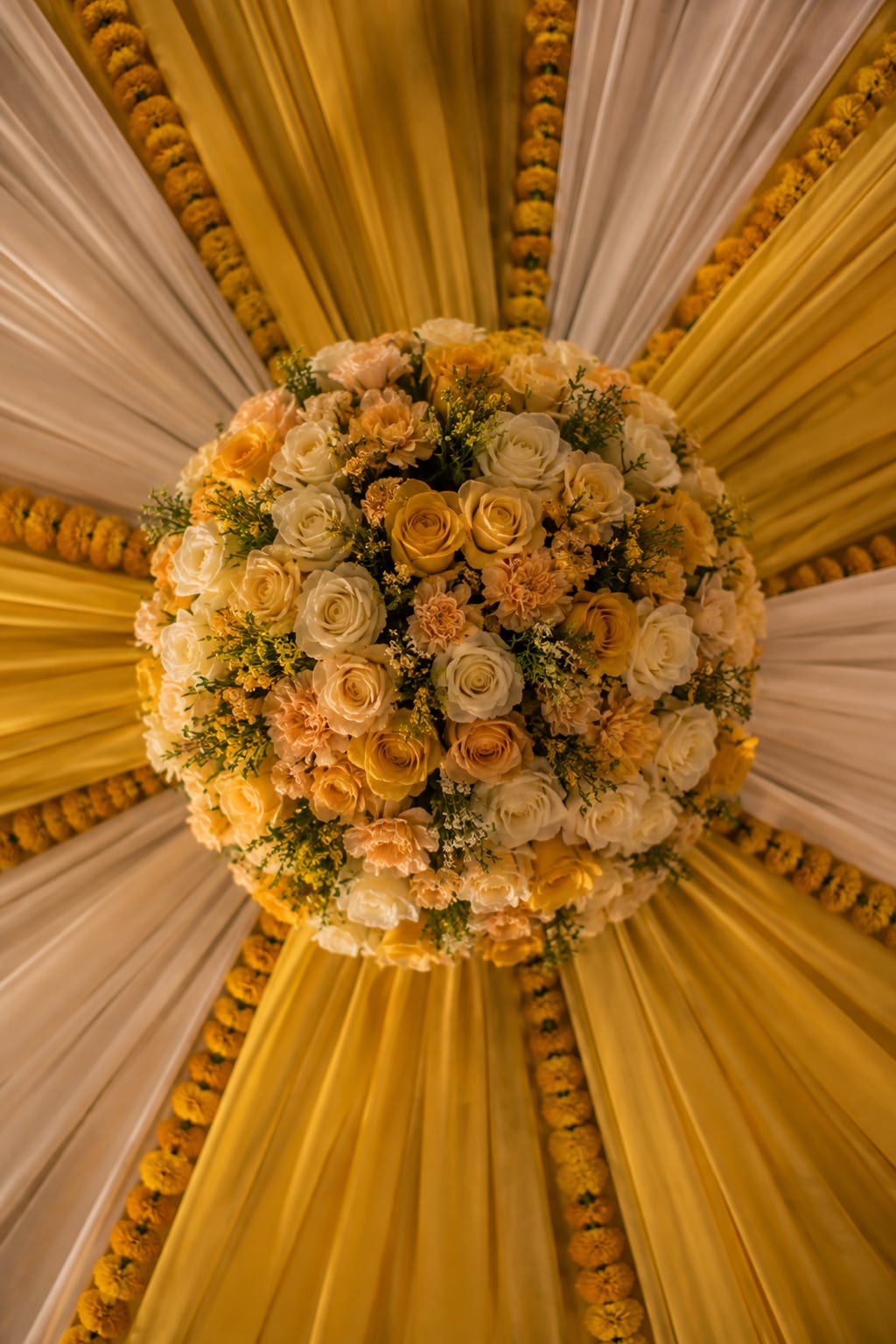 Looking up into a marigold-and-rose mehendi canopy