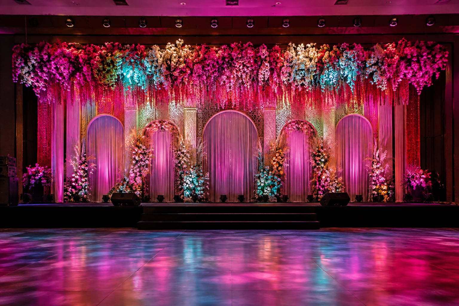 Sangeet stage backdrop, colour-lit floral valance