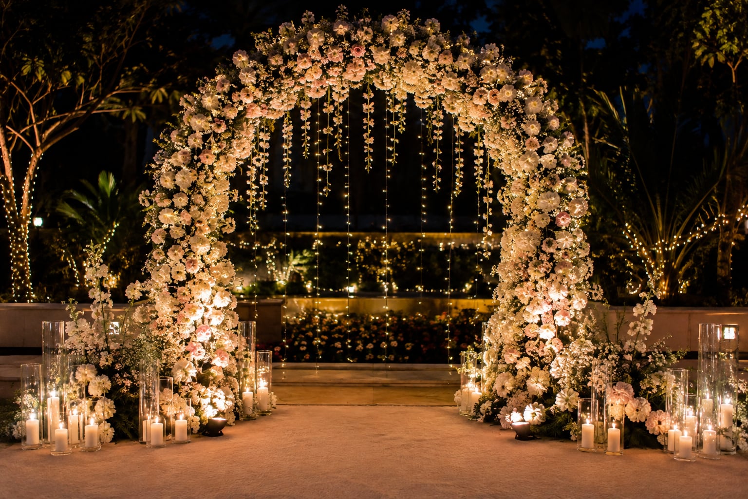 An elegant candlelit floral arch at dusk